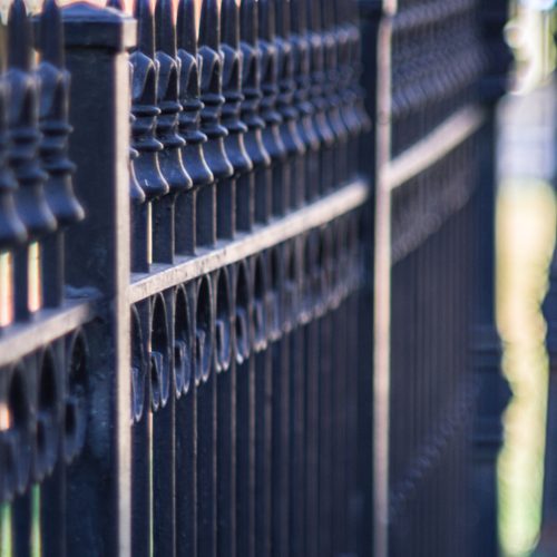 Vertical closeup shot of a metal fence on a sidewalk A vertical closeup shot of a metal fence on a sidewalk
